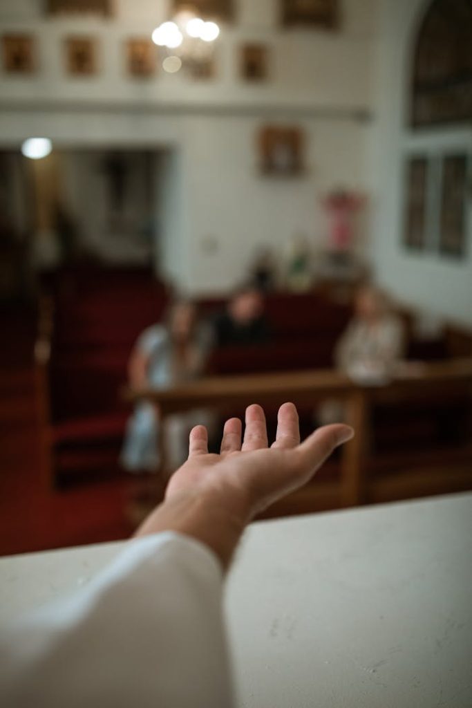 pexels-photo-5875311 A hand reaching out in a church setting, symbolizing faith and community.